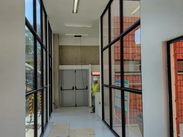Esquadria de vidro com perfil preto em corredor